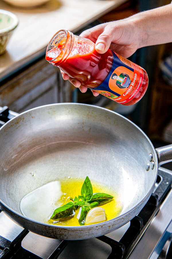 Aggiungi l'olio d'oliva, l'aglio e la passata nella padella